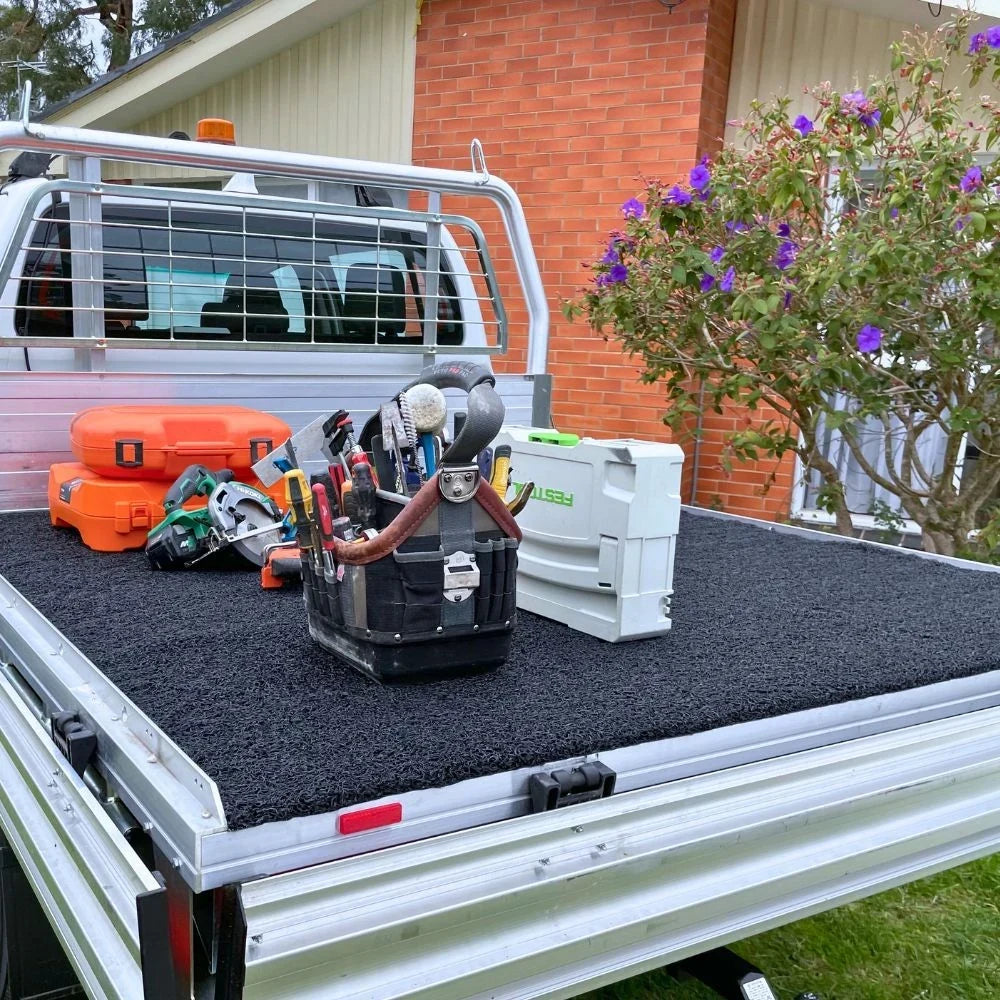 Tools and cargo resting on a coil ute tub mat